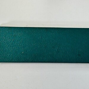 K&ouml;nnte beinhalten: Eine rechteckige, teal-farbene Box mit strukturierter Oberfl&auml;che. Die Box ist geschlossen und scheint aus einem strapazierf&auml;higen Material zu bestehen. Die Box befindet sich vor einem wei&szlig;en Hintergrund.