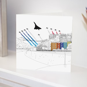 May include: A black and white illustration of a city skyline with a Concorde jet flying overhead. The city is depicted with colourful buildings and a bridge. The jet is leaving a trail of smoke in the sky.