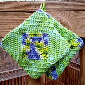 May include: Green, blue and yellow crocheted pot holder with a square design.