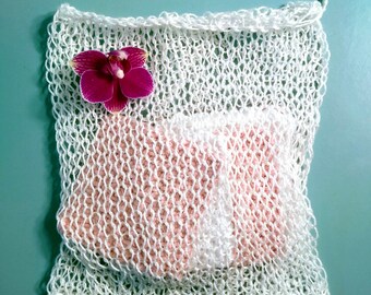 May include: White mesh laundry bag with a pink knitted insert and a pink orchid flower on top.