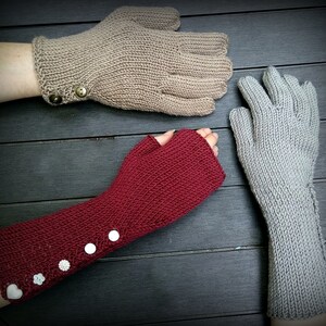 May include: Three pairs of knitted gloves in different colors and styles. One pair is beige with a button detail, another is red with white buttons, and the third is gray.