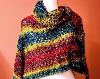 Può includere: Uno scialle all'uncinetto arcobaleno con un filo metallico scintillante. Lo scialle è drappeggiato su un manichino bianco.