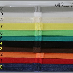 Pu&ograve; includere: Un set di 10 elastici per capelli di diversi colori, numerati da 10 a 20. Gli elastici sono disposti in una pila verticale, con il colore pi&ugrave; scuro in basso e il colore pi&ugrave; chiaro in alto. Il testo "All Season Bloom Supplies" &egrave; visibile nella parte superiore dell'immagine.