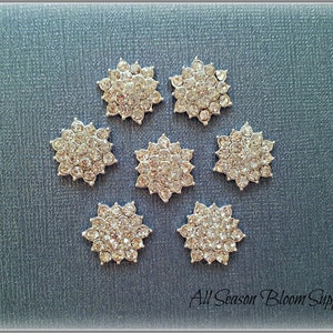 May include: Seven silver-toned, star-shaped embellishments with clear rhinestones. Each star has a diameter of approximately 1 inch.