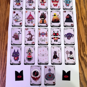 May include: A set of 22 tarot cards featuring illustrations of various characters and symbols. The cards are printed on white paper with a light pink background. The cards are arranged in a grid pattern, with each card having a black border. The cards are numbered from 0 to 21, and each card has a name printed on it. The cards are all in the same style, with a cartoonish aesthetic.