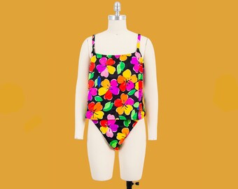 Puede incluir: Un traje de baño negro con estampado floral de colores. El traje de baño tiene un top estilo tanque y una parte inferior de corte alto.