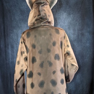 May include: A brown hooded sweatshirt with a spotted pattern. The hood has large, pointed ears.