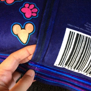 May include: A blue plush pillow with a colorful paw print and Mickey Mouse design. The pillow has a purple, blue, and white striped trim. The back of the pillow has a barcode and the text "https://www.etsy.com/ca-en/shop/comical"