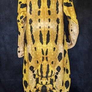 Puede incluir: Un disfraz de gecko leopardo de cuerpo entero con un patr&oacute;n amarillo, negro y blanco. El disfraz tiene una capucha con una cara de gecko realista y una cola larga.