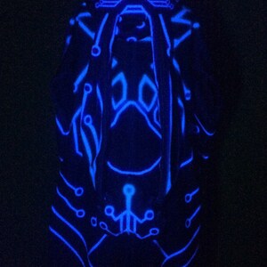 May include: A blue glow-in-the-dark figure with a circuit board design. The figure is standing on a black background.
