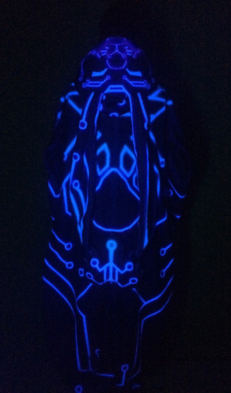May include: A blue glow-in-the-dark figure with a circuit board design. The figure is standing on a black background.