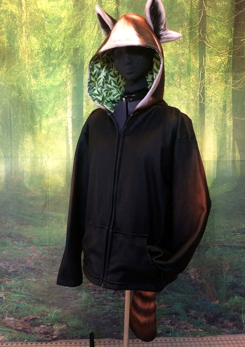Puede incluir: Sudadera negra con cremallera y capucha con dise&ntilde;o de panda rojo en la capucha y la cola. El forro de la capucha es verde con un patr&oacute;n de hojas.