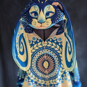 May include: A blue and yellow hooded sweatshirt with a mandala pattern and a matching blue and yellow cat face hood.