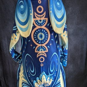 May include: A blue and yellow hooded jumpsuit with a moon and star pattern. The hood has large, floppy ears.