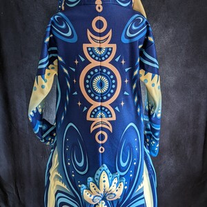 May include: A blue and yellow hooded jacket with a mandala design on the back. The jacket has a long, flowing silhouette and a hood with a drawstring.