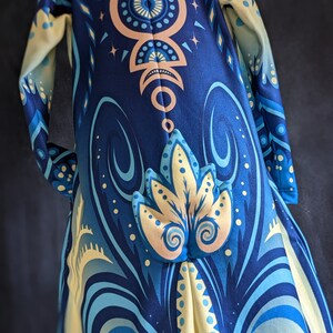 May include: A blue and yellow patterned hooded robe with a geometric design. The robe has a long, flowing silhouette and a hood with a pointed tip.