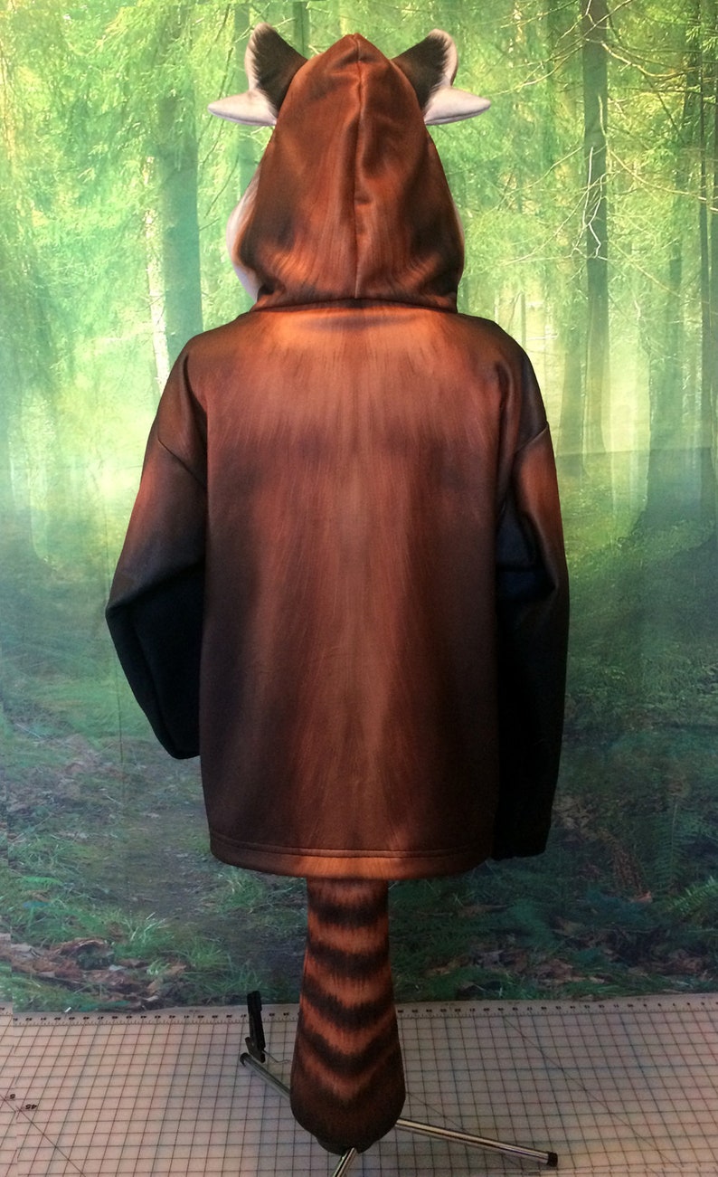 Puede incluir: Una sudadera con capucha marr&oacute;n y negra con un dise&ntilde;o de panda rojo. La capucha tiene orejas y la cola est&aacute; unida a la parte inferior de la sudadera.