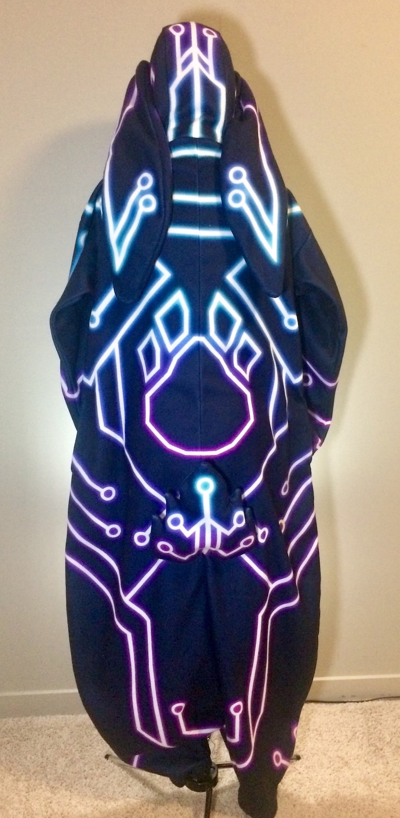 May include: A black hooded sweatshirt with a neon blue and purple circuit board design. The hood has two bunny ears.