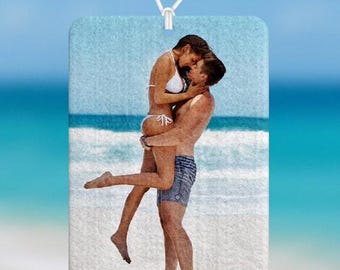 May include: Rectangular car air freshener with a beach scene featuring a couple embracing. The air freshener is hanging from a car's rearview mirror. The text "Jen's Custom Printing" is visible at the bottom.