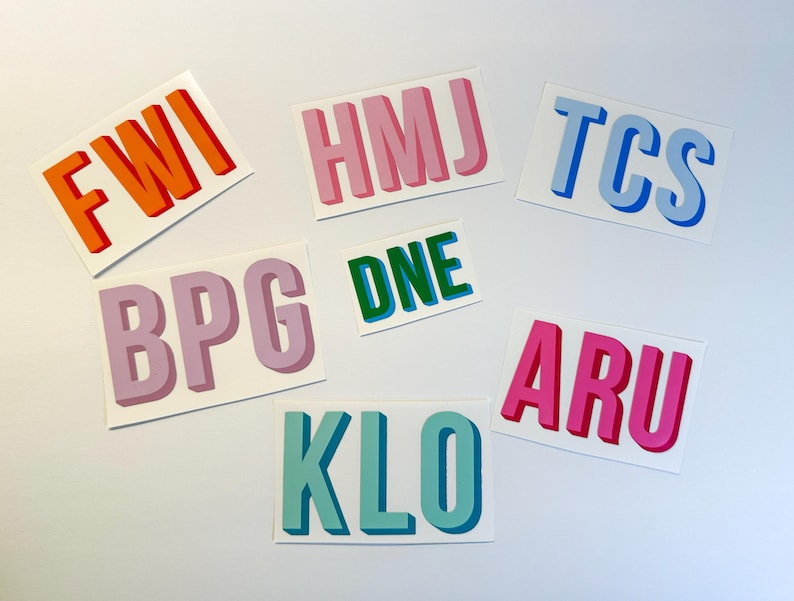Puede incluir: Siete pegatinas de colores con diferentes letras que deletrean las palabras "FWI", "HMJ", "TCS", "BPG", "DNE", "ARU" y "KLO".