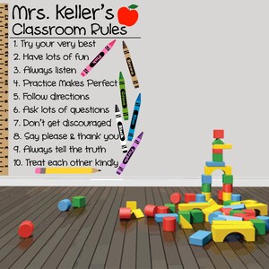 May include: Classroom rules poster with a red apple and a ruler. The rules are written in black text and include: Try your very best, Have lots of fun, Always listen, Practice makes perfect, Follow directions, Ask lots of questions, Don't get discouraged, Say please & thank you, Always tell the truth, Treat each other kindly.