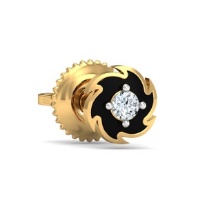 May include: A gold earring with a black swirl design and a clear diamond in the centre.