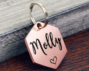 May include: Rose gold hexagon-shaped pet ID tag with a silver key ring. The tag is engraved with the name "Molly" and a small heart.