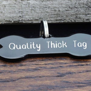 May include: Black bone-shaped dog tag with the text "Quality Thick Tag" engraved in white.