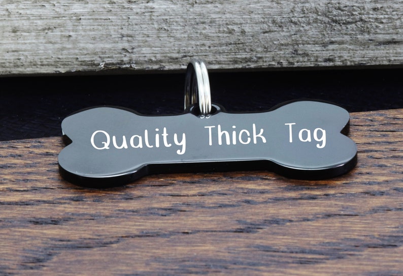 May include: Black bone-shaped dog tag with the text "Quality Thick Tag" engraved in white.