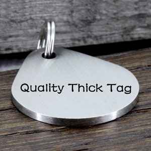 May include: Silver teardrop-shaped key chain tag with the text "Quality Thick Tag" engraved on the front.