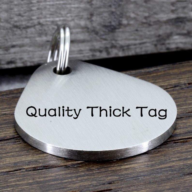 May include: Silver teardrop-shaped key chain tag with the text "Quality Thick Tag" engraved on the front.