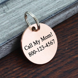 May include: Round copper dog tag with a silver key ring. The tag has the text "Call My Mom! 800-123-4567" engraved on it.