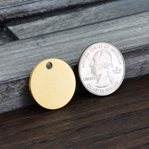 May include: A gold-colored round metal tag with a hole for a ring or chain. The tag is about the size of a US quarter.