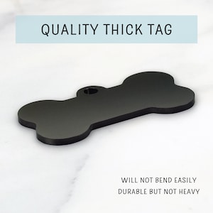 May include: Black bone-shaped dog tag with a hole for a ring.  "QUALITY THICK TAG" is printed in white on a light blue background.  "WILL NOT BEND EASILY DURABLE BUT NOT HEAVY" is printed in black on a white background.