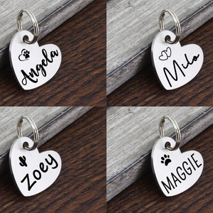 May include: Four silver heart-shaped dog tags with key rings. The tags are engraved with the names "Angela", "Milo", "Zoey", and "Maggie" and have paw print or heart designs.