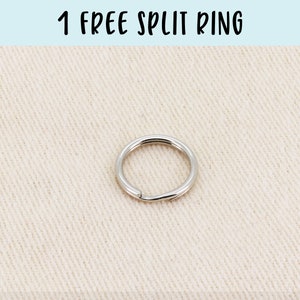 May include: A silver split ring, a metal ring that opens and closes, on a beige fabric background. 1 FREE SPLIT RING is written in black text at the top of the image.