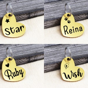 May include: Four gold heart-shaped pet ID tags with different designs and names. The tags feature a star, paw prints, a heart, and a dandelion. The names on the tags are Star, Reina, Ruby, and Wish.