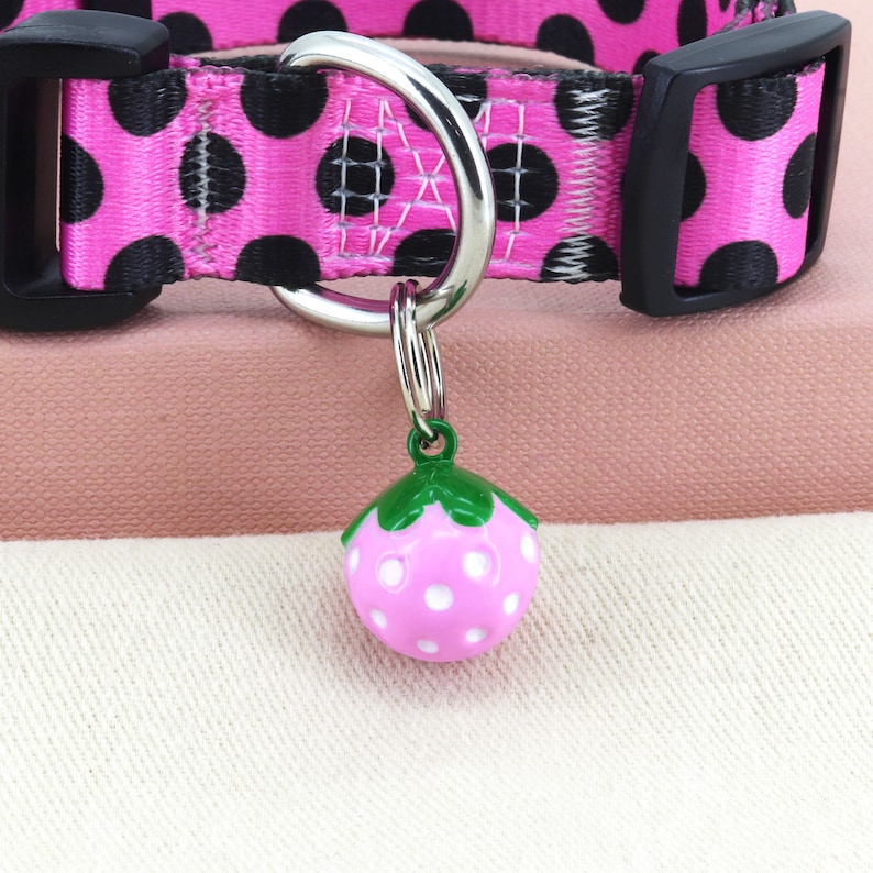 May include: Pink and black polka dot dog collar with a silver D-ring and a pink and white strawberry charm.