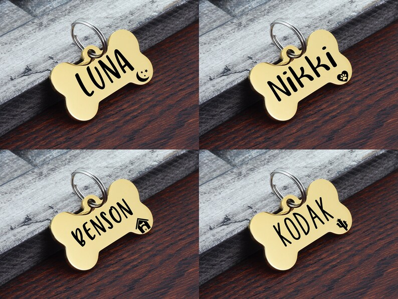 May include: Four gold bone-shaped dog tags with engraved names and small icons. The names are "Luna", "Nikki", "Benson", and "Kodak".