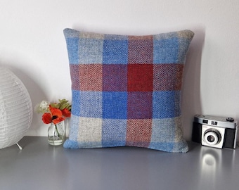 May include: A blue, red, and beige plaid throw pillow with a herringbone pattern.