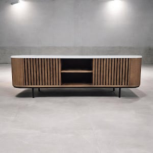 Può includere: Una consolle multimediale moderna, bianca e in legno con un fronte curvo e gambe in metallo nero. La consolle ha uno scaffale e due ante con doghe di legno verticali.