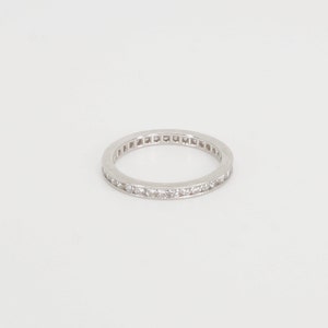 Op de afbeelding: Een zilveren bandring met een rij kleine diamanten die in de band zijn gezet.