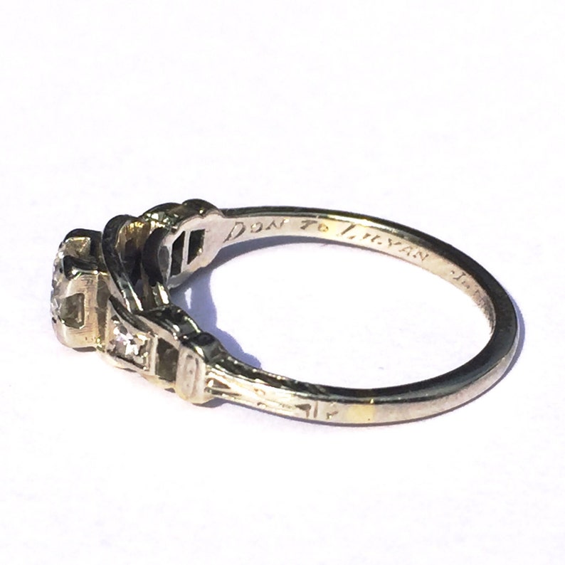 May include: A silver ring with a central diamond and smaller diamonds on the band. The inscription on the inside of the band reads "Don to Tristan".
