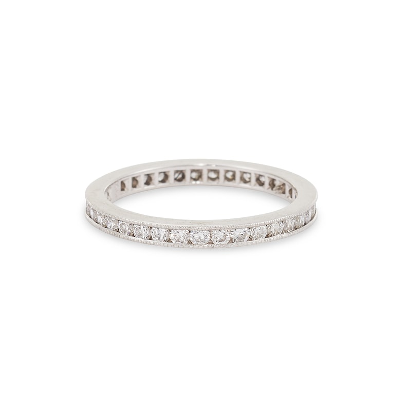 Op de afbeelding: Een dunne zilveren band met een rij kleine diamanten die in een kanaalsetting zijn gezet.