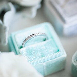 Op de afbeelding: Een zilveren ring met kleine diamanten in een lichtblauwe fluwelen ringendoos.