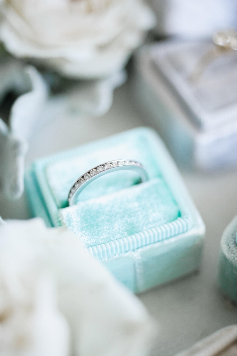 Op de afbeelding: Een zilveren ring met kleine diamanten in een lichtblauwe fluwelen ringendoos.