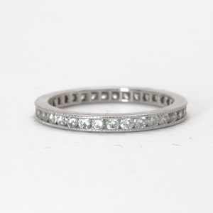 Op de afbeelding: Een zilveren bandring met een rij kleine, ronde diamanten die in een kanaalsetting zijn gezet.
