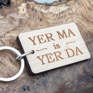 May include: Wooden keychain with a silver ring and the text "Yer Ma is Yer Da" engraved on it.