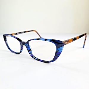 May include: Spectacles featuring a cat-eye frame with a blue and black striped pattern on the front. The temples are made of a brown and black tortoiseshell material. The lenses are clear and the frame has a glossy finish throughout the structure.