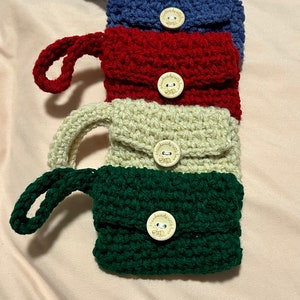 May include: Four crocheted pouches with wooden buttons. The pouches are in blue, red, beige, and green. Each button has the text "handmade with love" on it.